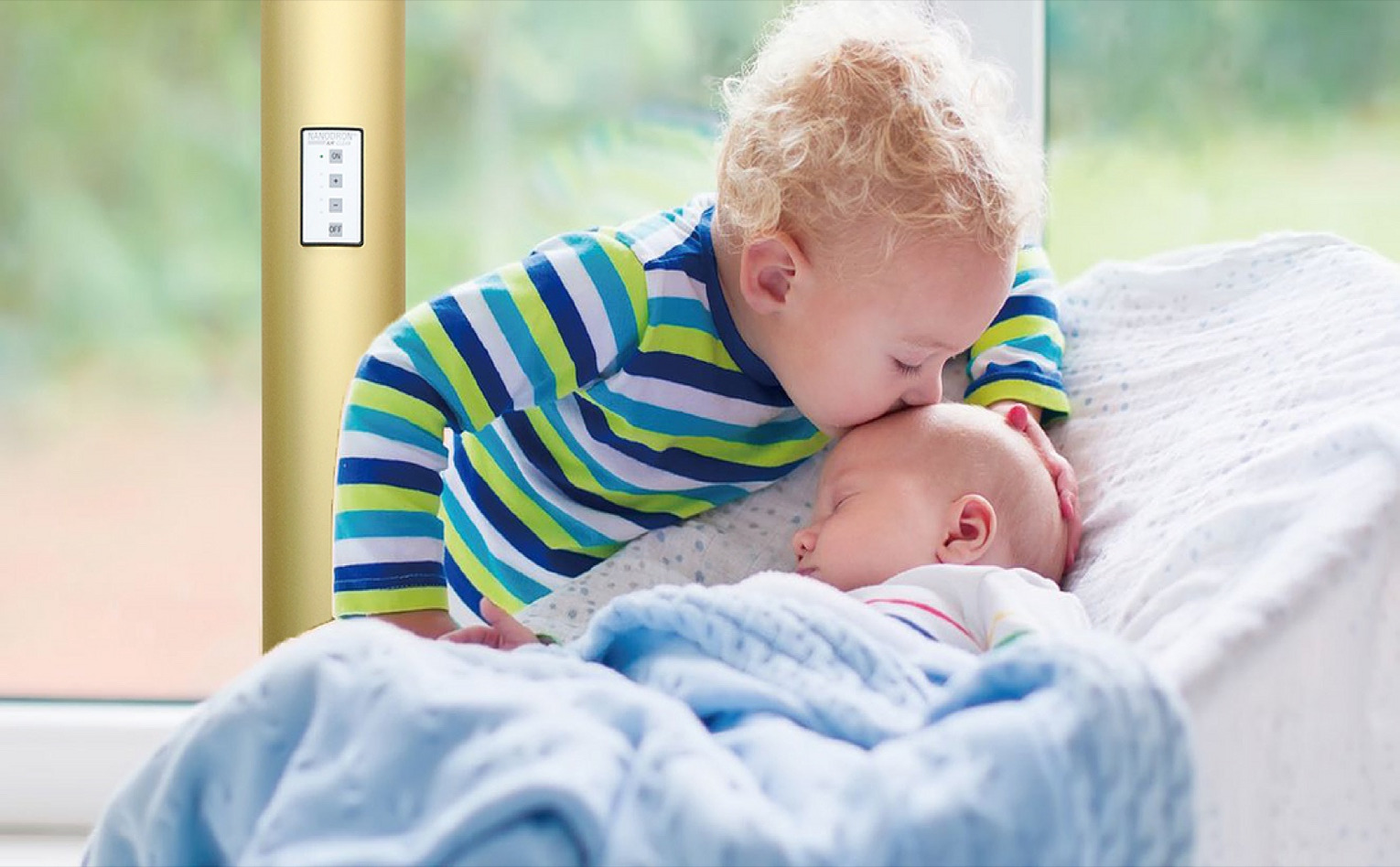 眠る赤ちゃんと幼い兄弟のそばに置かれたナノドロン空気清浄機